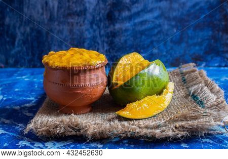 Sweet Mango Pulp In Earthen Bowl And Ripe Mango On Burlap Fabric Isolated On Bluish Background