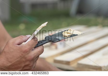 Putty On Spatula Tool In Male Hands Closeup, Repairing Wood With Paste.