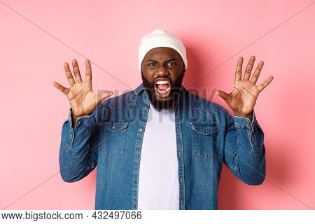 Angry African-american Guy In Beanie, Scare You, Roaring And Screaming, Showing Hands, Standing Ove 