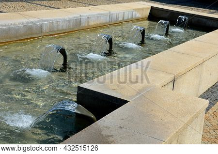 Swimming Pool With Fountains In The Shape Of An Opposite Cross On The Promenade In The Park On The S