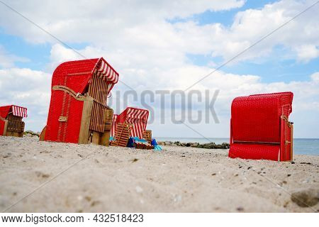Traditional German Roofed Wicker Beach Chairs On The Beach Of Baltic Sea. Beach With Red Chairs On S