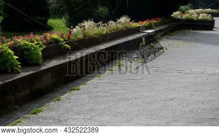On The Edge Of The Elevated Terrace Overlooking The Park Is A Concrete Long Flowerpot With A Concret