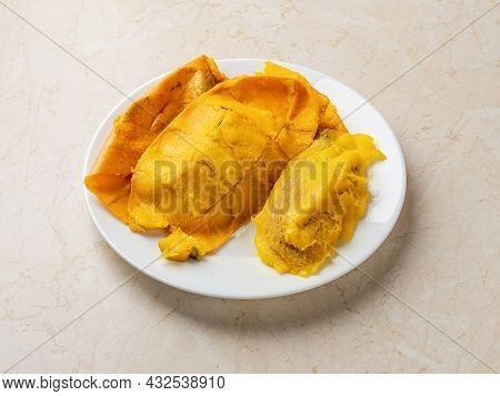 Yellow Mango Skin And Large Pit On A Whte Plate Over Kitchen Table. Fresh Ripe Mango Seed And Peelin