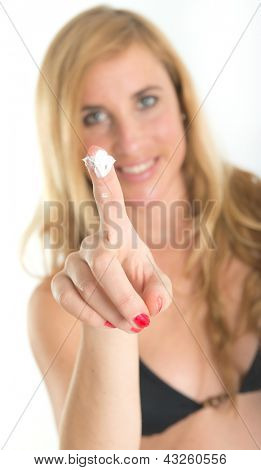 Ragazza in beachwear proponendo sun block crema allo spettatore