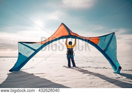 Sporty Girl Stands And Hold Snowkite In Hands. Winter Kitesurfing Concept