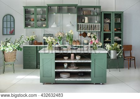 Green Kitchen Interior With Furniture. Stylish Cuisine With Flowers In Vase. Wooden Kitchen In Sprin