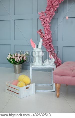Two Ceramic Statuette Easter Bunnies Stand On A White Wooden Table. Easter Interior Home. Easter Hun