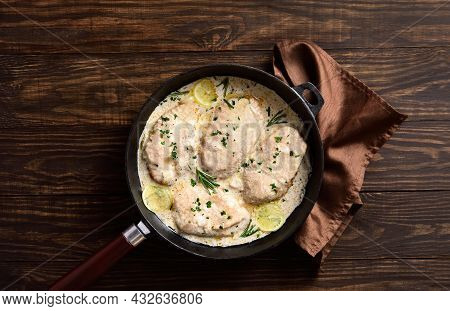 Chicken Breast In Creamy Garlic Sauce In Cast Iron Pan Over Wooden Background With Free Text Space. 