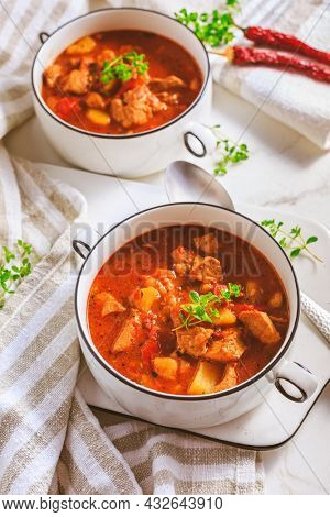 Beef goulash soup - hearty Hungarian soup of meat and vegetables seasoned with paprika on white background