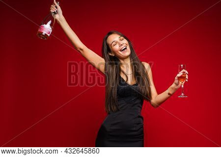 Beautiful Female Fashion Model In Black Dress Drinks Champagne And Rejoices