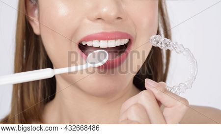 Young Smiling Woman Holding Invisalign Braces In Studio, Dental Healthcare And Orthodontic Concept