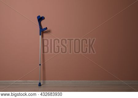 Elbow Crutch Near Pale Pink Wall. Space For Text