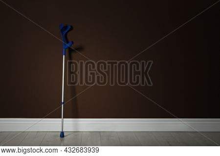 Elbow Crutch Near Brown Wall. Space For Text