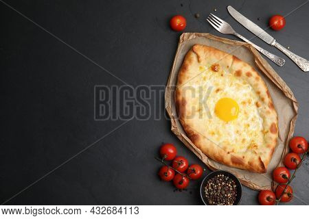Fresh Delicious Adjarian Khachapuri Served On Black Table, Flat Lay. Space For Text