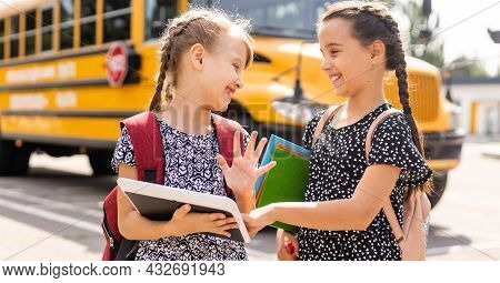 Cheerful Little Girls Next To School Bus. Backback. Back To School Concept.