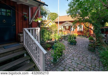 Vastervik, Sweden - 08.23.2021: Wide Shot Of Yard Of Old, Traditional Red Wooden House In Scandinavi