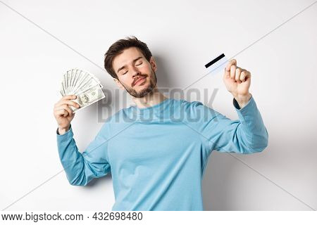 Carefree Male Model Dancing With Money And Credit Card, Smiling And Dreaming Of Shopping, Standing O