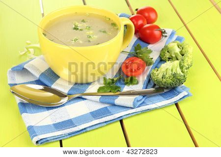Dietní polévka se zeleninou v poháru na zelený dřevěný stůl detail