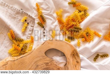 Fragment Of Cutting Board Curved Shape Of Olive Tree, Scattered Around Pasta, Garlic, Pepper. They L