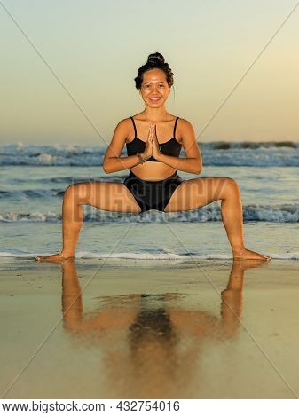 Beach Yoga Practice. Young Woman Practicing Utkata Konasana, Goddess Pose. Hands In Namaste Mudra. O