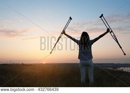 Woman Holding Axillary Crutches Outdoors At Sunrise, Back View. Healing Miracle