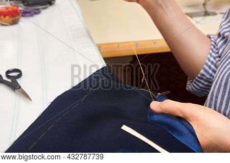 Woman Tailor Wrapped Up In Sewing Jacket With Needle And Thread While Sitting At Working Table. Suit