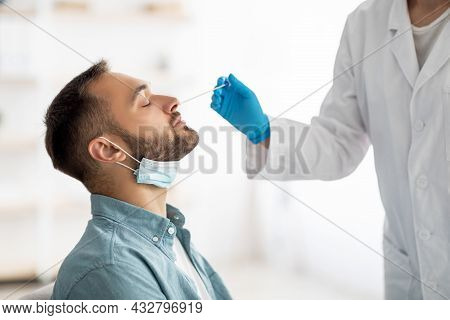 Coronavirus Testing Procedure. Doctor Making Nasal Pcr Test For Millennial Guy, Using Swab Stick At 