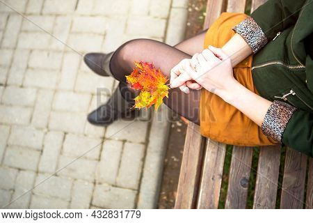 Legs Of A Woman In Nylon Tights In A Closed Pose Leg Over Leg In A Short Mustard Mini Skirt And In A