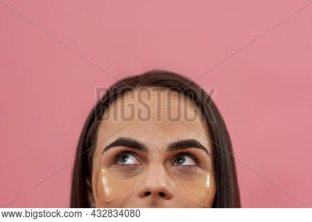 Half Face Closeup Of Young Transgender With Dark Brown And Applied Under Eye Gel Patches Looking Up,