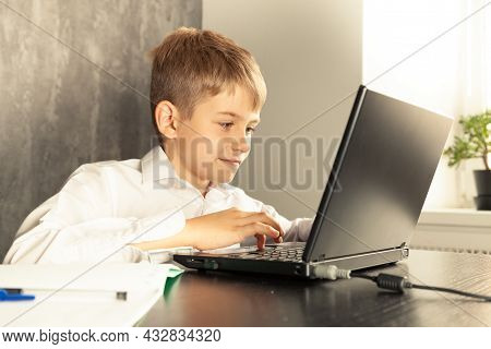 A Schoolboy Boy Studies At Home And Does School Homework.