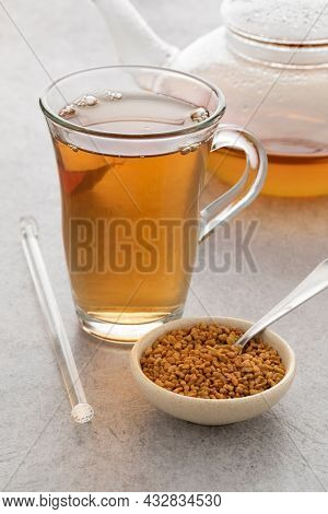 Glass cup with fresh Fenugreek tea and a bowl with Fenugreek seeds  