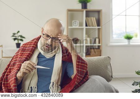 Sick Man Who Has Cold Or Flu Fever Takes His Temperature And Looks At Thermometer
