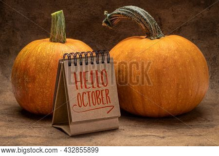 Hello October welcome note  - handwriting in a desktop calendar with pumpkins, fall season concept