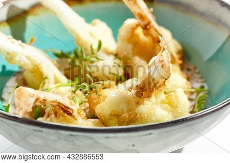Fried tempura cauliflower with peanut sauce in bowl. Vegeterian hot dish - florets cabbages roasted  in batter on white background. Veggie menu for asian restaurant. Hot vegan appetizers plant based