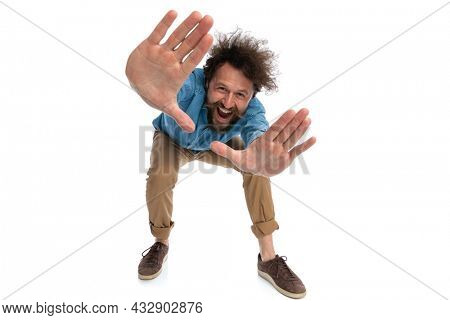 sexy casual man leaning forward and framing with happiness on white background