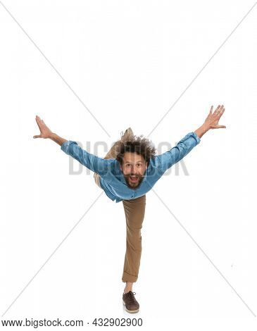 handsome casual man leaning forward and standing on one leg only on white background