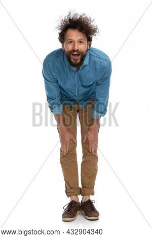 casual young man leaning forward and feeling surprised against white background