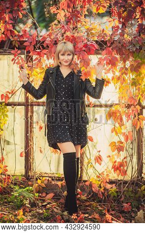 Young Woman With Bob Haircut And Fringe In A Black Leather Jacket And High Black Jackboots Is Standi