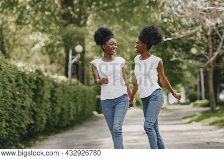Twin Sisters Holding Hands And Walking In A Park