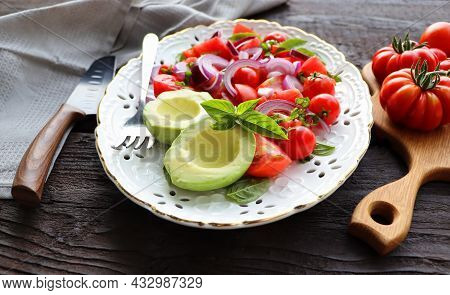 Fresh Healthy Avacado And Tomato Salad With Onions On Dark Rusric Background .