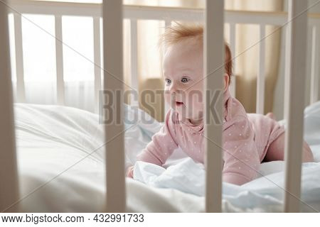 Cute baby girl crowling on white linen in her cradle after sleep