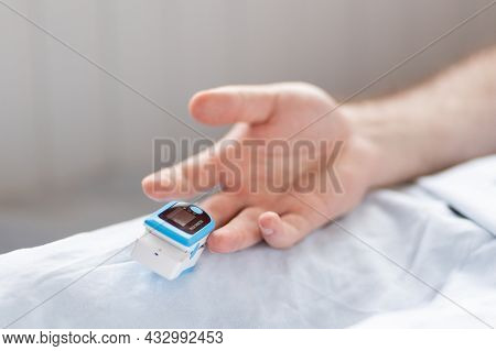Determination Of Oxygen In The Blood. Male Hand With A Pulse Oximeter On The Middle Finger, Close-up