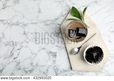 Glass Of Milk With Grass Jelly On White Marble Table, Top View. Space For Text