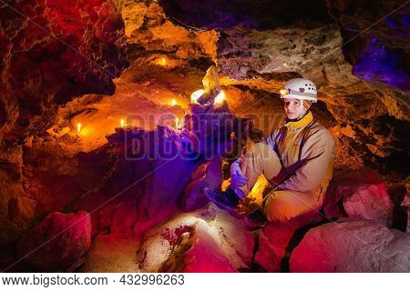 Women Explore The Beautiful Stone Cave Mlynky In Ukraine. Multicolored Light Shines On The Stones. E