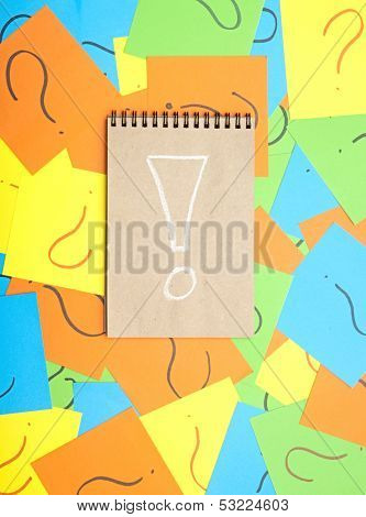 Pile of colorful paper notes with question marks and note book with exclamation mark 