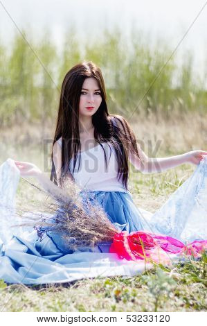 Young beautiful girl sitting in spring field