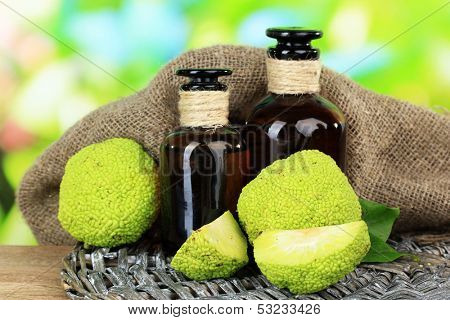 Osage Orange fruits (Maclura pomifera) and medicine bottles, on wooden table, on nature background
