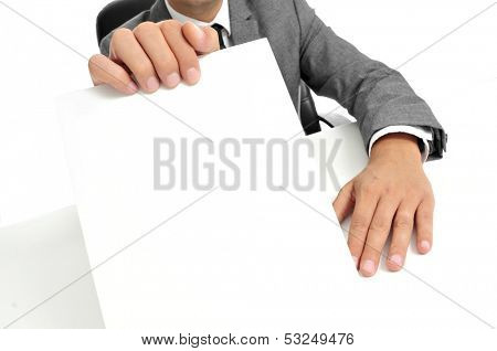 a man wearing a suit sitting in a desk holding a blank signboard with a copy-space