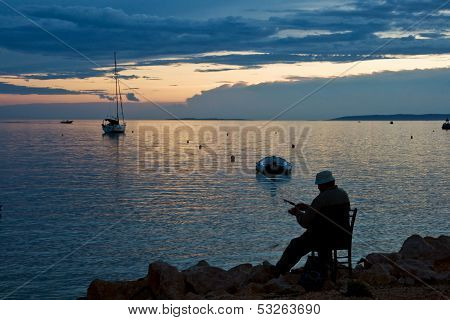 NOVALJA, ISLAND PAG, CROATIA - CIRCA SEPTEMBER 2010 - Man fishing on sunset