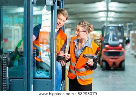 Logistics Teamwork - forklift driver, Worker or warehouseman and his coworker with scanner at warehouse of freight forwarding company